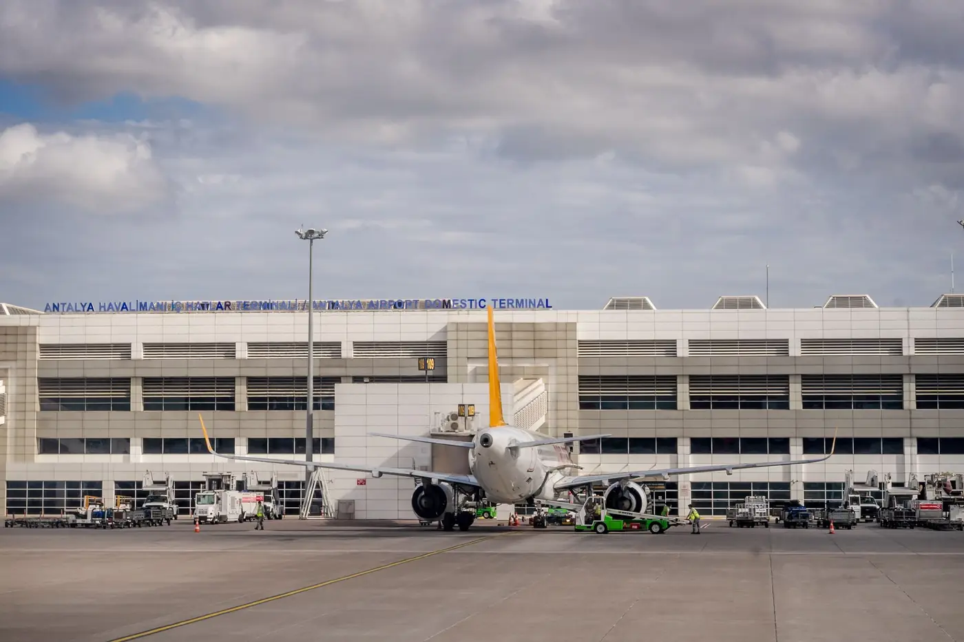 Vliegtuig geparkeerd bij de terminal van een luchthaven onder een bewolkte lucht