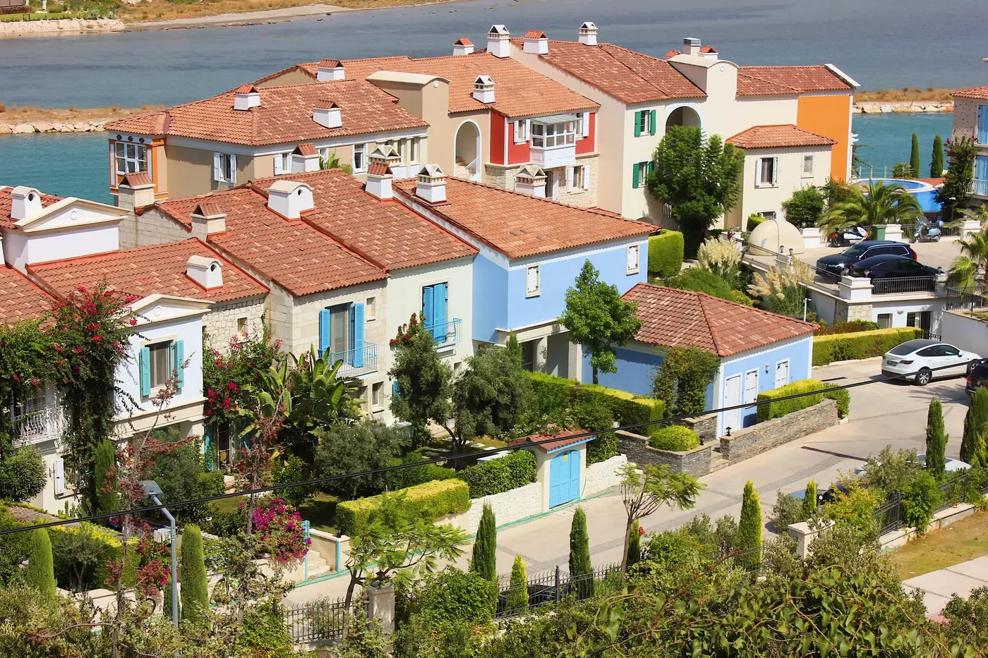 Rij woningen tegen een heuvel aan de Turkse kust, met boten op het water ervoor