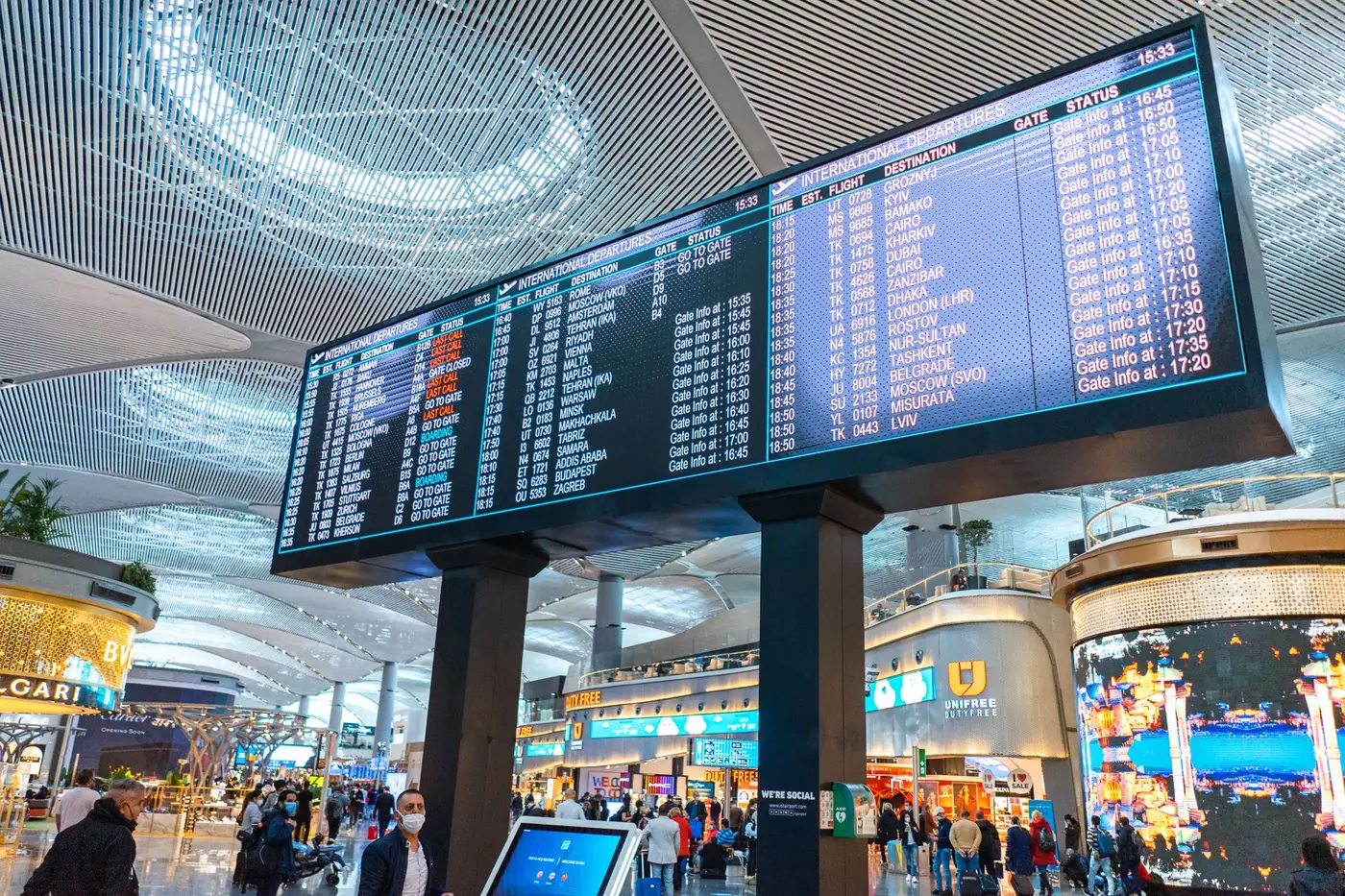 Passagiers lopen door de vertrekhal van een Turkse luchthaven langs winkels en informatieschermen