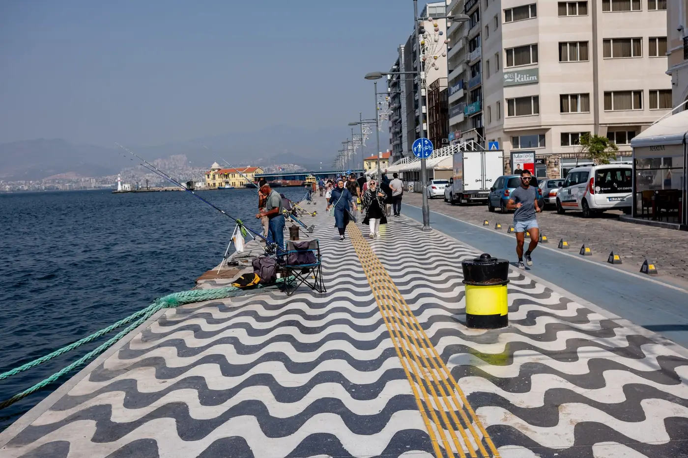 Wandelaars en vissers op de kademuur van de kustboulevard van Izmir