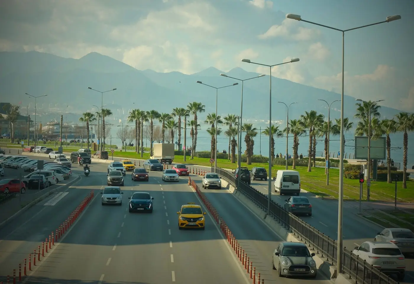 Drukke kustweg in Turkije met verkeer, palmbomen en bergen op de achtergrond