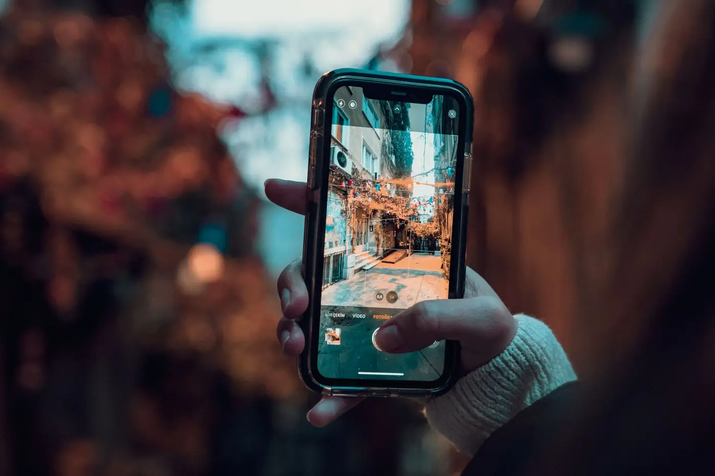 Hand houdt een smartphone vast tijdens het fotograferen van een straat in Istanbul