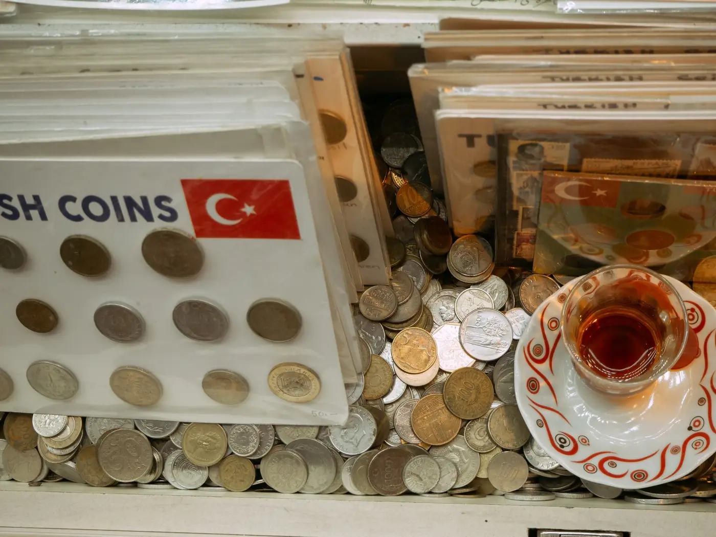 Zilveren en gouden Turkse munten naast een traditioneel Turks theeglas