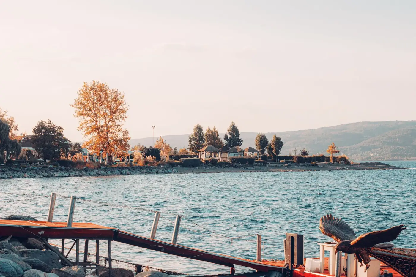 Peaceful lake view with autumn trees and a pier in Turkey.