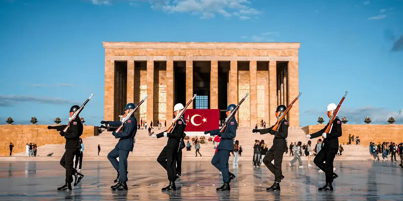Soldiers performing a ceremonial march at Anıtkabir with Turkish flag in the background.