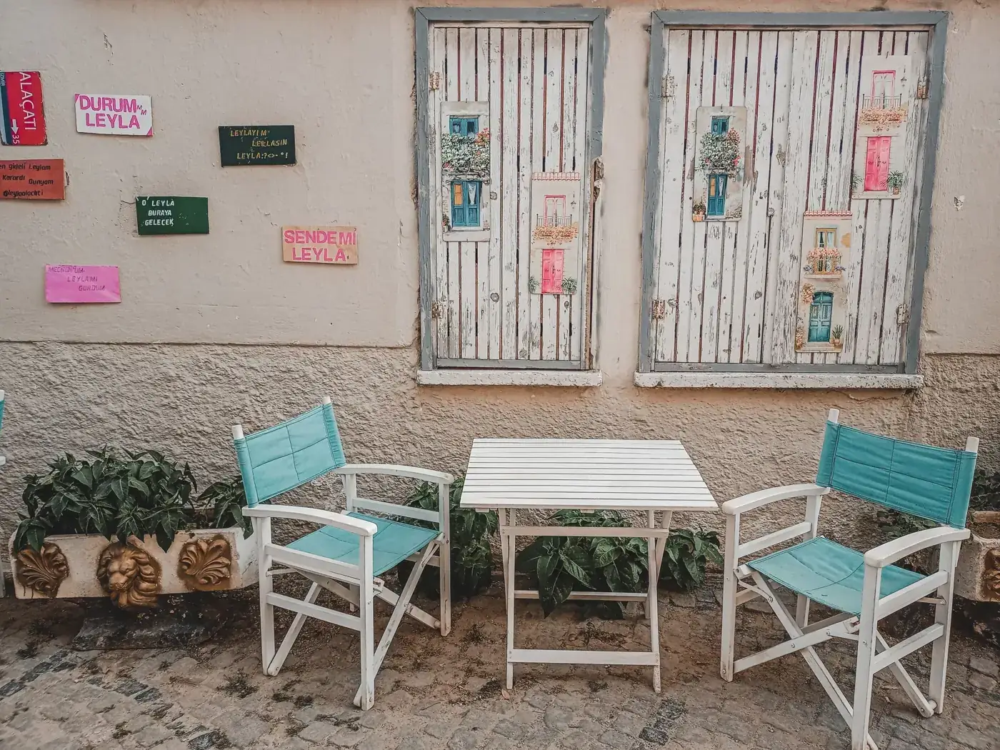 A quaint outdoor cafe scene with turquoise chairs and rustic wall decor.