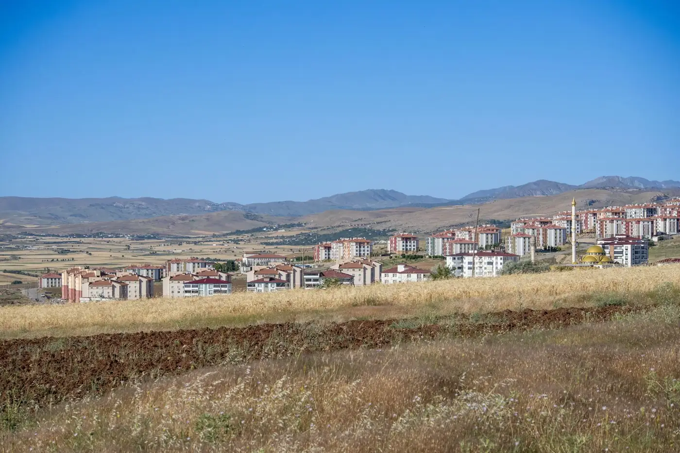 Expansive view of Palu, Elazığ showcasing modern housing against scenic mountain backdrop.