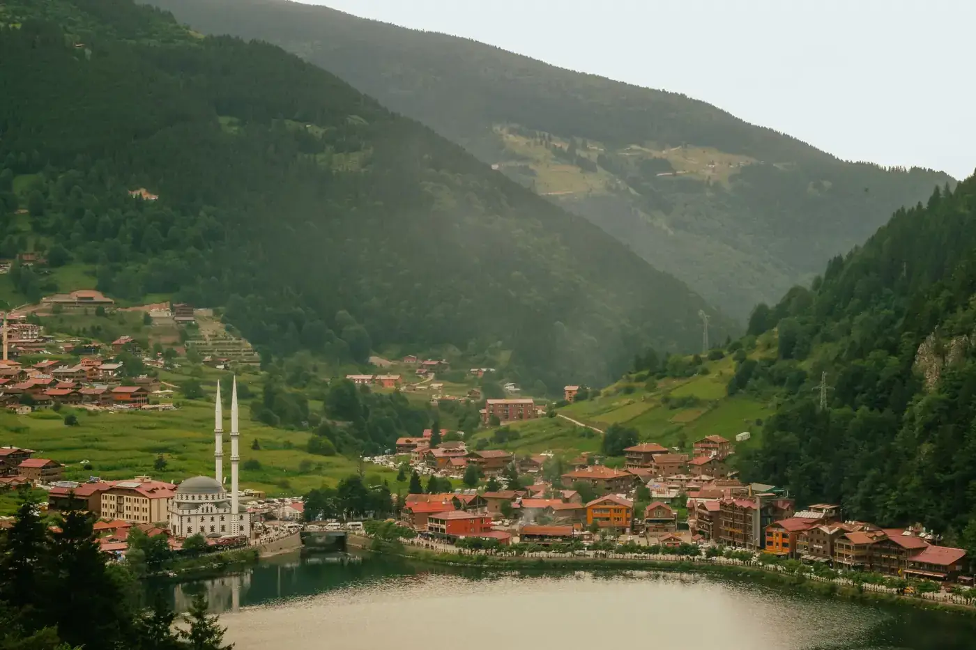 Idyllic view of Uzungöl village by the lake surrounded by lush hills in summer.