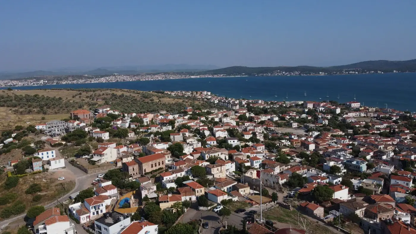 Aerial shot of Ayvalık's charming houses and coastline under a clear blue sky in summer.