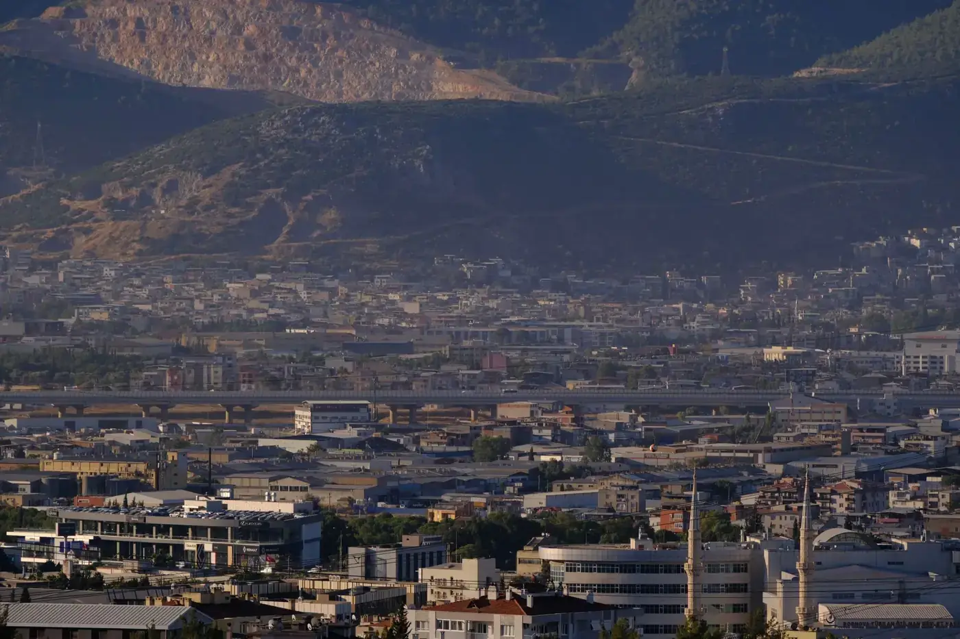 Aerial view of İzmir's urban landscape with mountainous backdrop under a clear sky.
