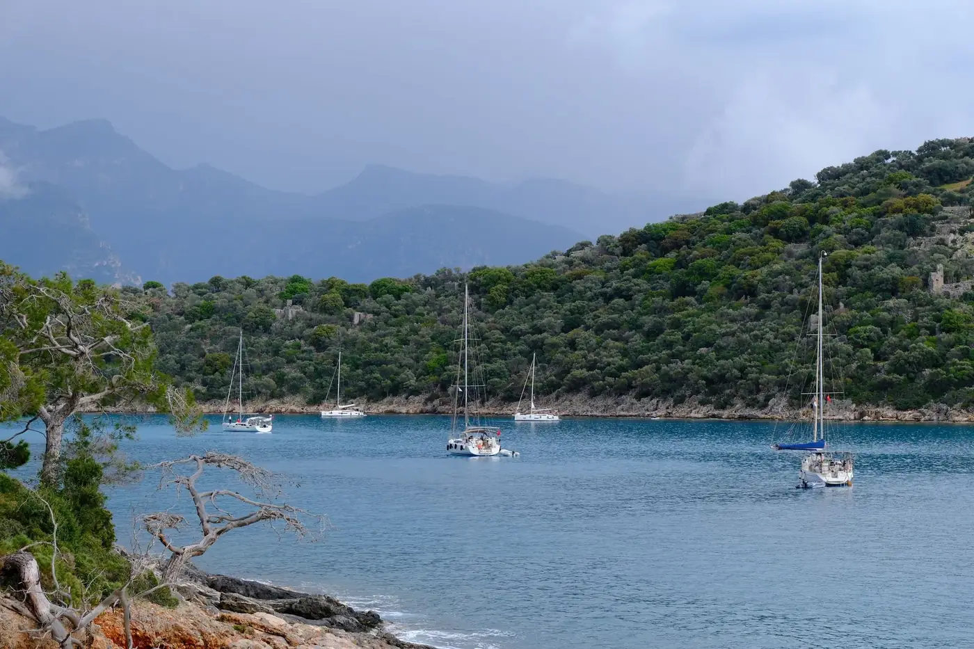Idyllic sailboats anchored in the picturesque bay of Fethiye, Turkey, under a cloudy sky.