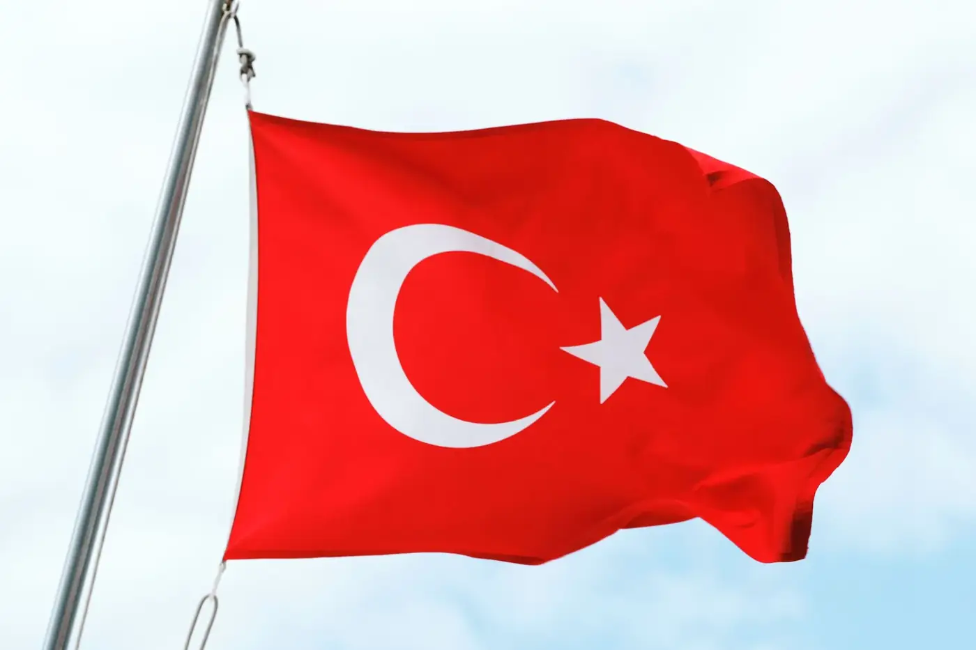 The Turkish national flag elegantly waving against a clear blue sky, symbolizing national pride.