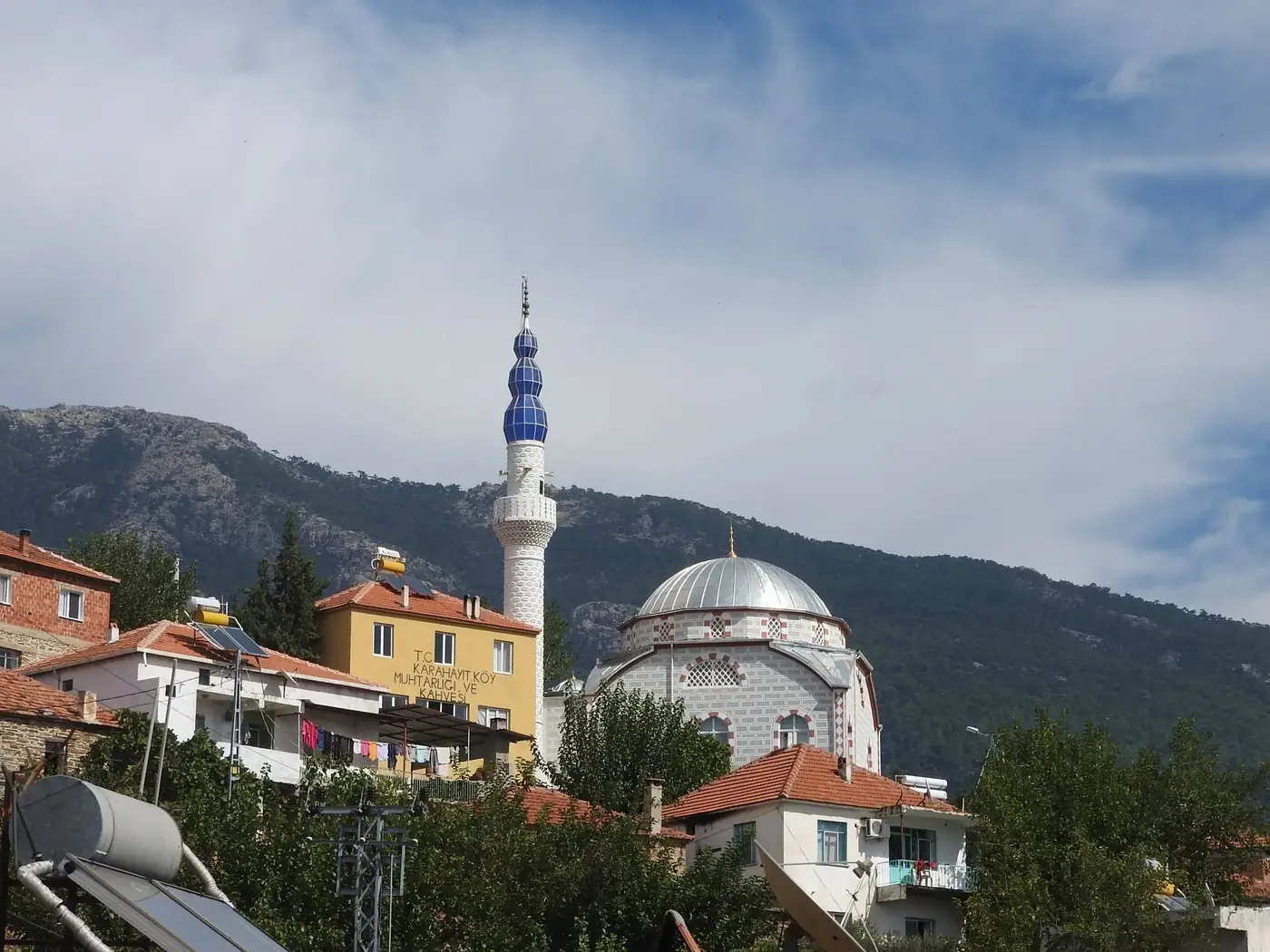 Beautiful mosque with a minaret against a mountainous backdrop under a clear sky.