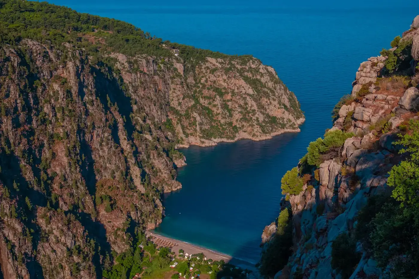 Stunning aerial shot of Butterfly Valley's turquoise waters surrounded by cliffs under summer sun.
