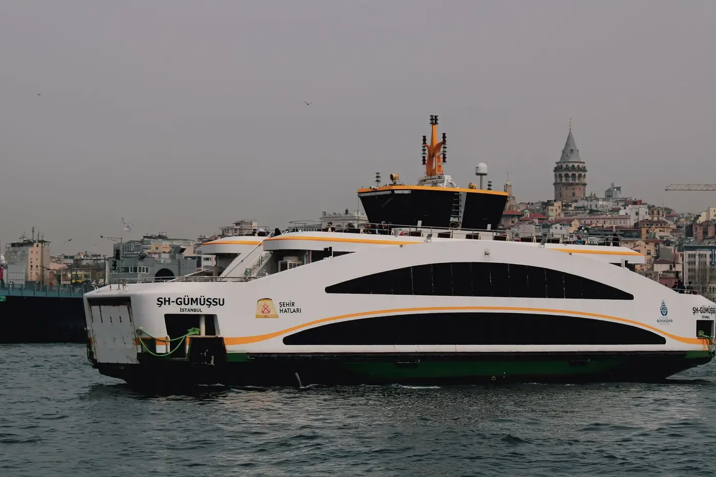 Modern ferry sailing in Istanbul with iconic Galata Tower in the background.