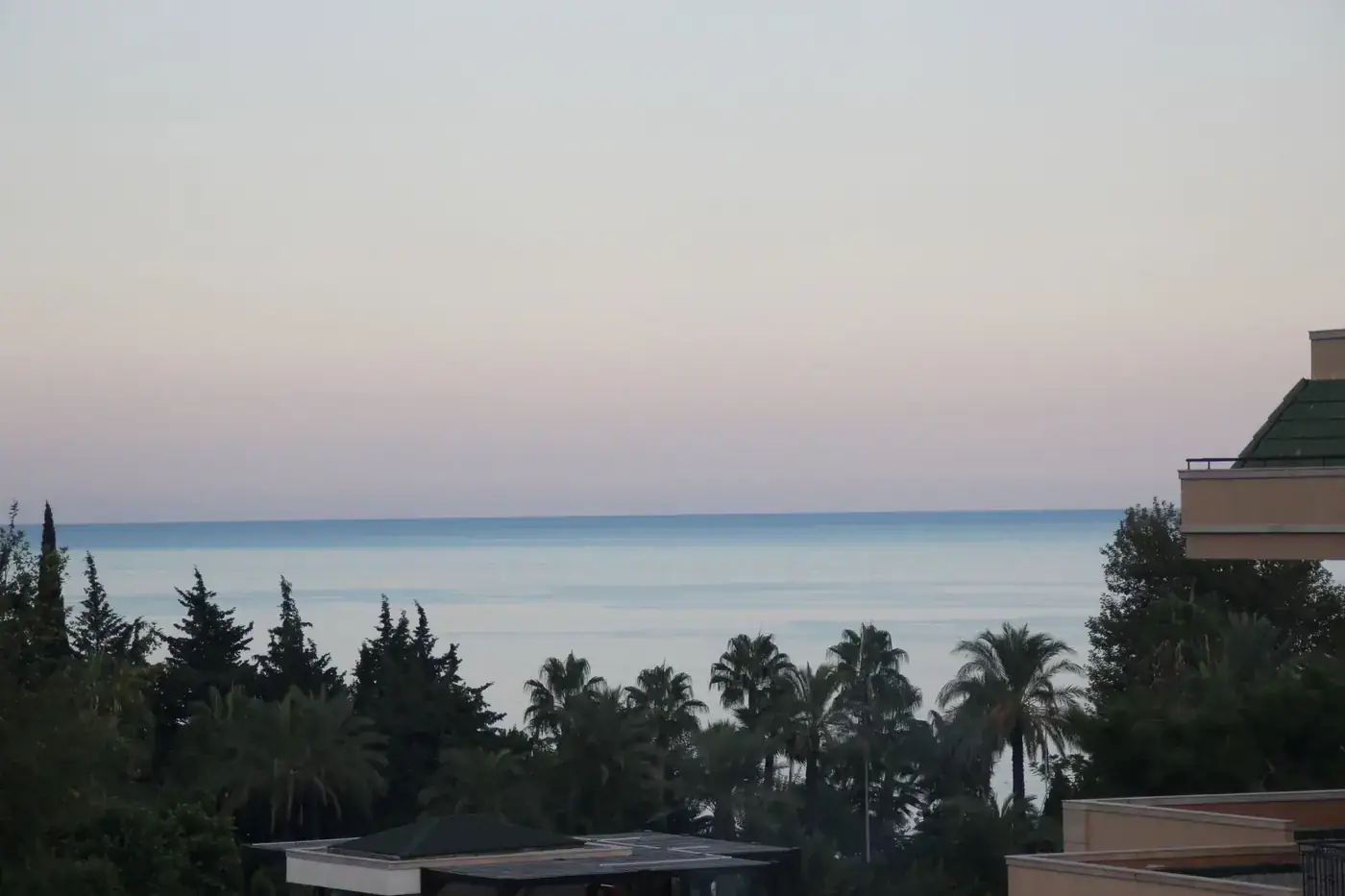 Scenic view of the Mediterranean Sea from Antalya with palm trees and a clear sky.