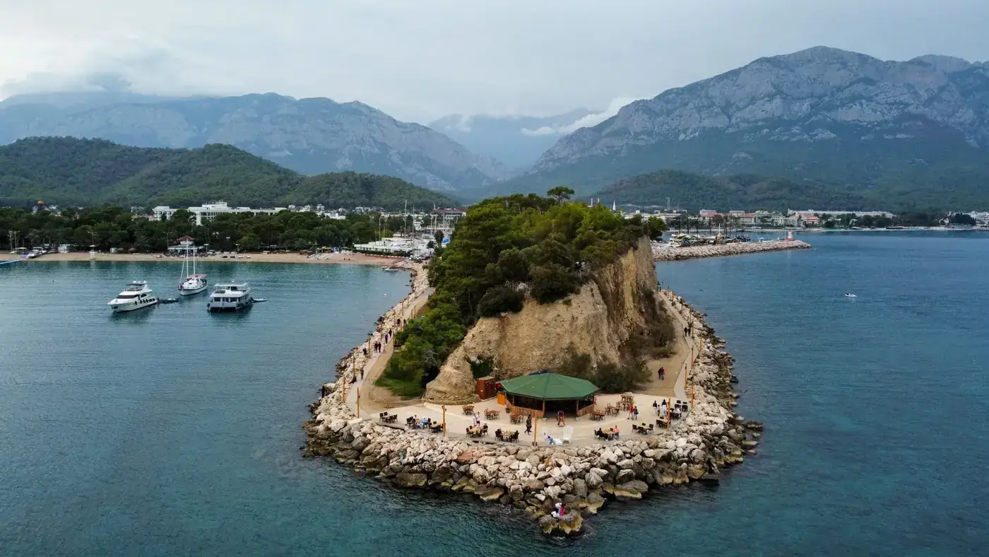 Aerial view of a picturesque peninsula with boats and mountainous backdrop.