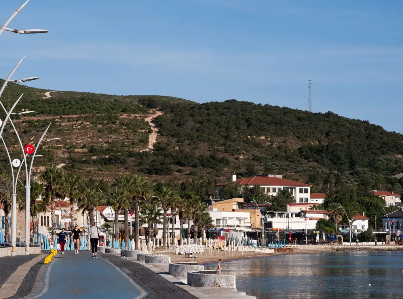 A beautiful coastal promenade in Foça, İzmir with a hillside backdrop, perfect for a relaxing stroll.