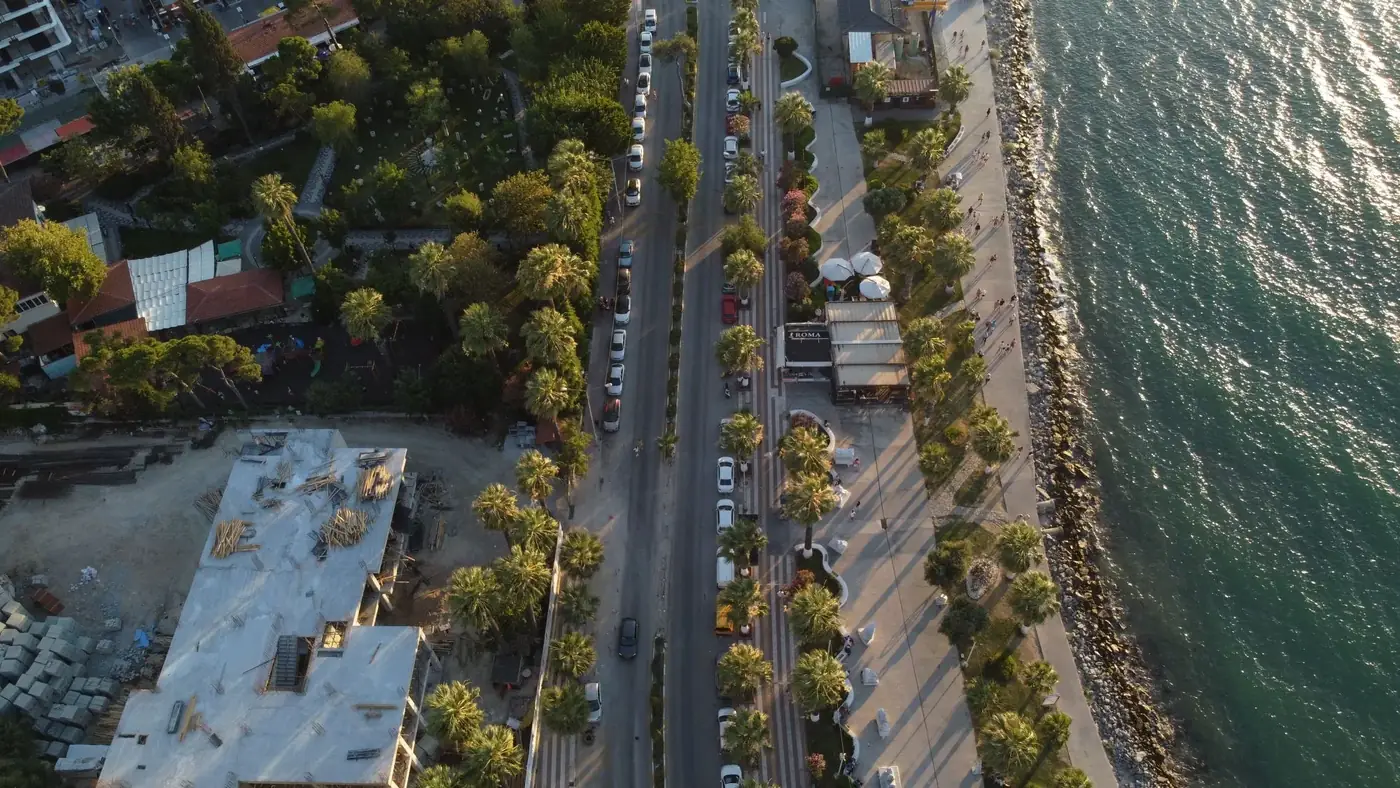 Aerial shot of Kuşadası's seafront and lush cityscape, featuring palm-lined streets.