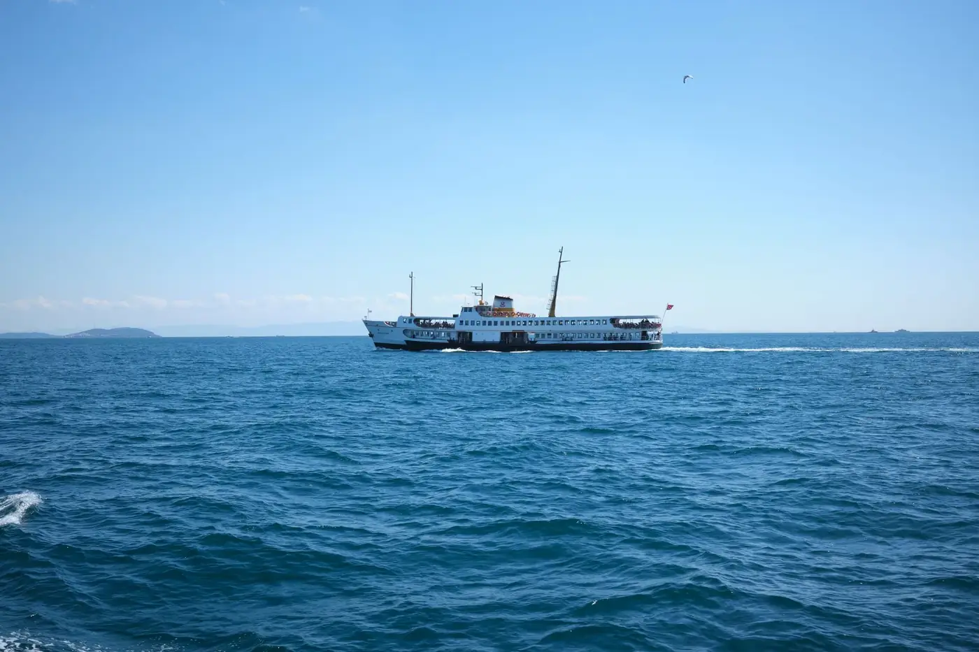 A serene ferry journey across Istanbul's blue waters under a clear sky.