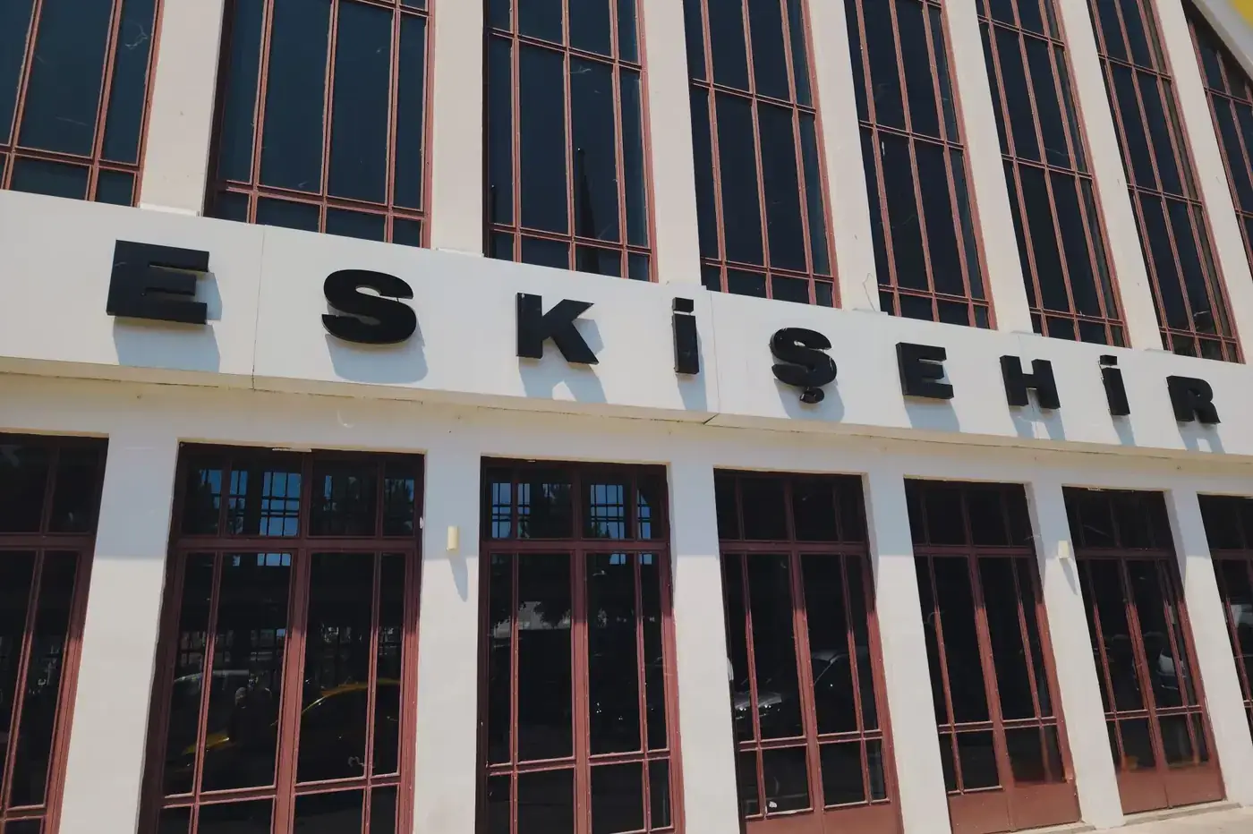 Exterior view of Eskişehir railway station with prominent signage on a sunny day.