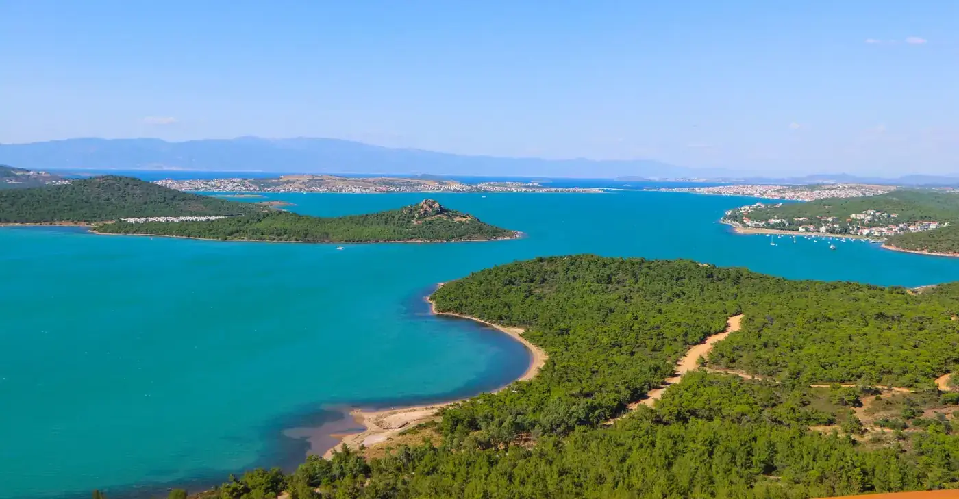 Breathtaking aerial view of Ayvalık's coastline with turquoise waters and lush forests.