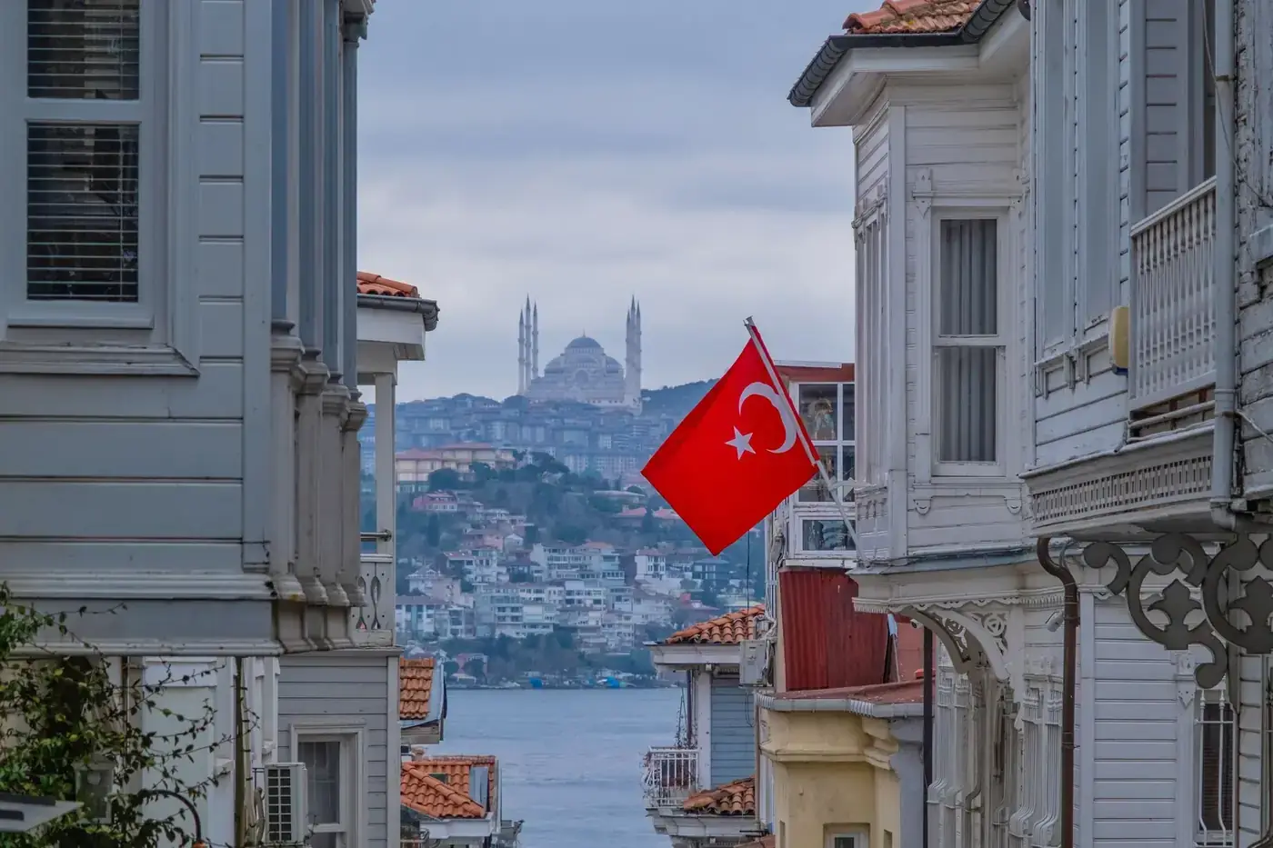 View of Istanbul's skyline featuring a Turkish flag and mosque on a cloudy day.