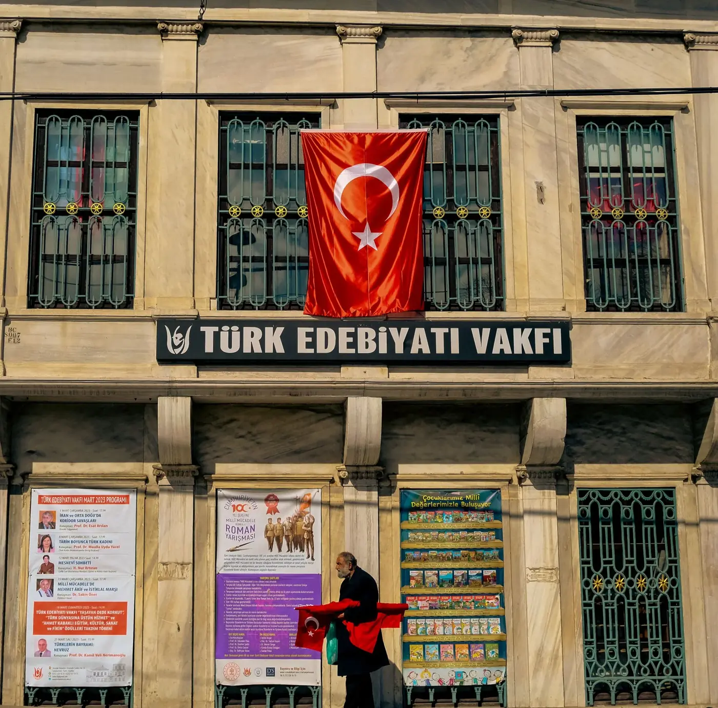 Building facade with Turkish flag and man walking in Istanbul.