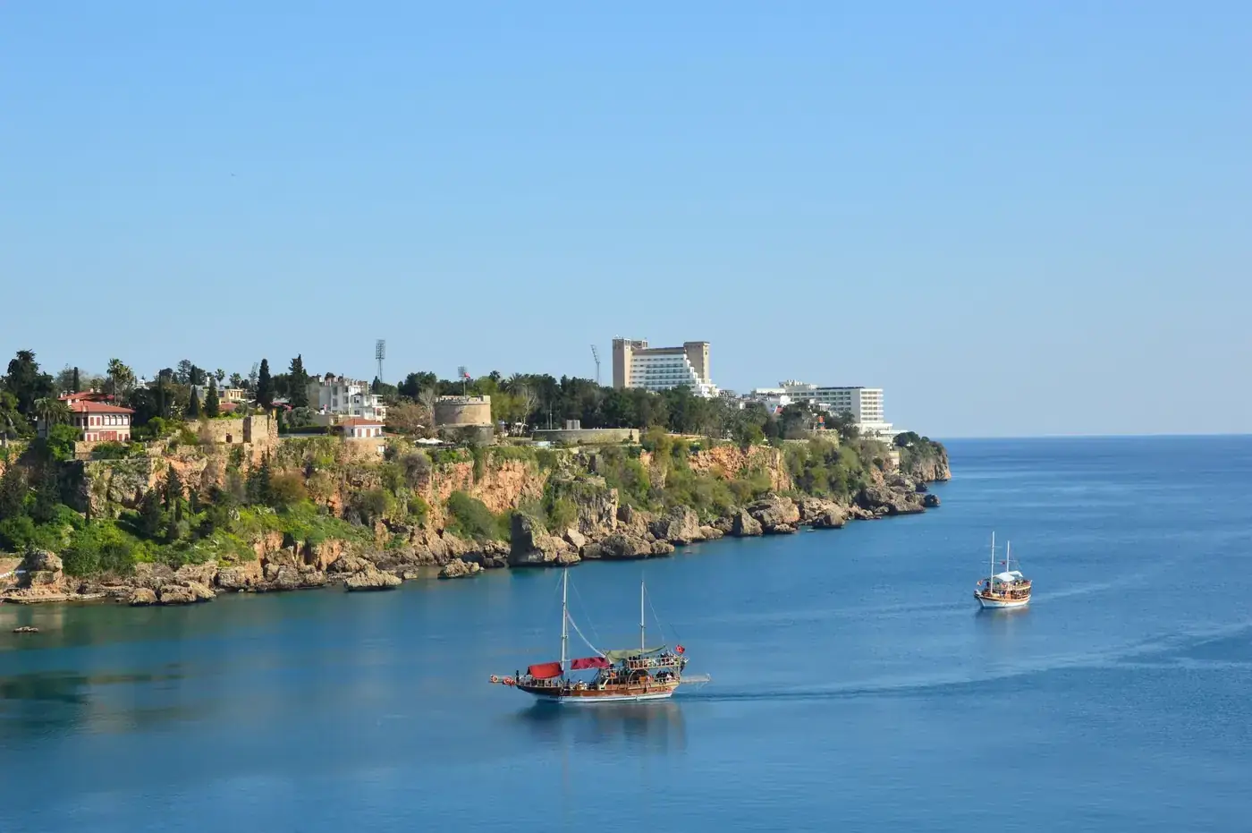 Explore the breathtaking coastal view of Antalya, Türkiye, featuring boats and stunning cliffs.