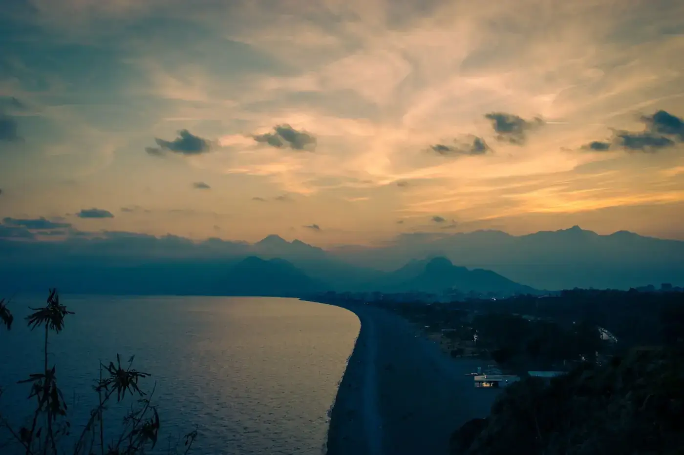 Stunning sunset view of Antalya's coastline with mountains and the serene Mediterranean Sea.