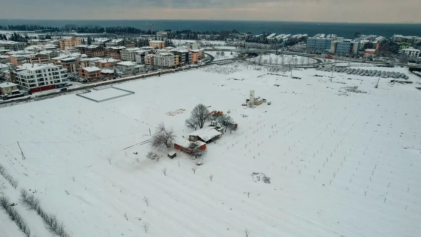 Aerial view of snow-covered fields and buildings in Yalova, Turkey during winter.