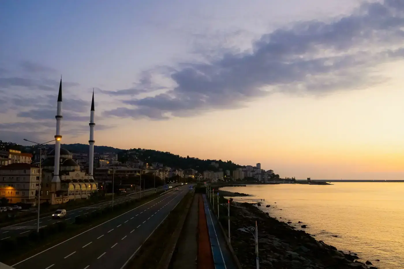 A serene sunset view over Pazar's coastal road and mosque in Rize, Turkey.