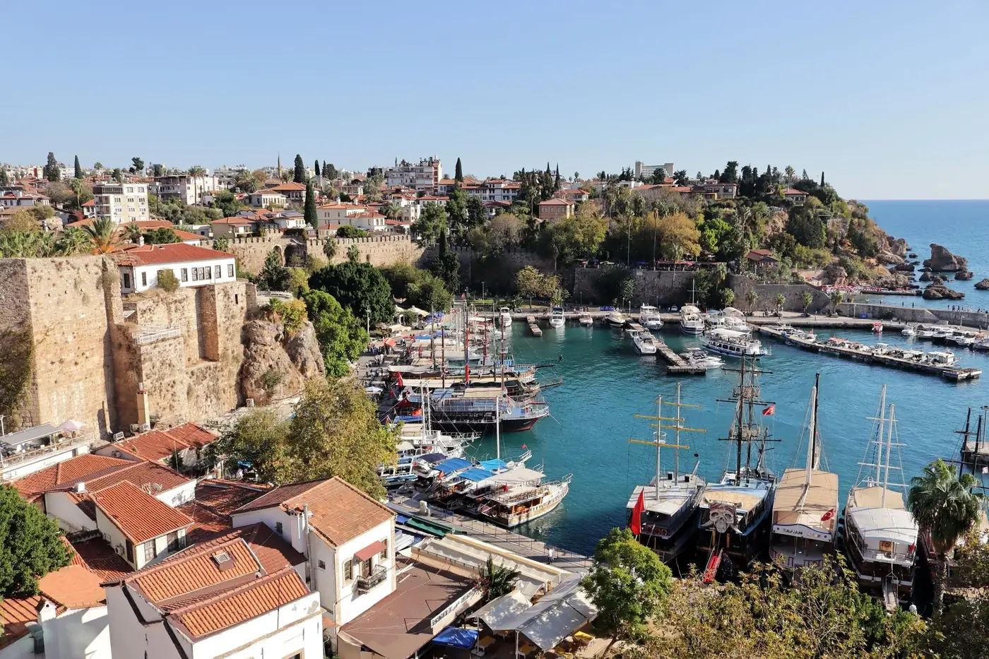 A stunning aerial view of Antalya's historic harbor with yachts and surrounding architecture on a sunny day.